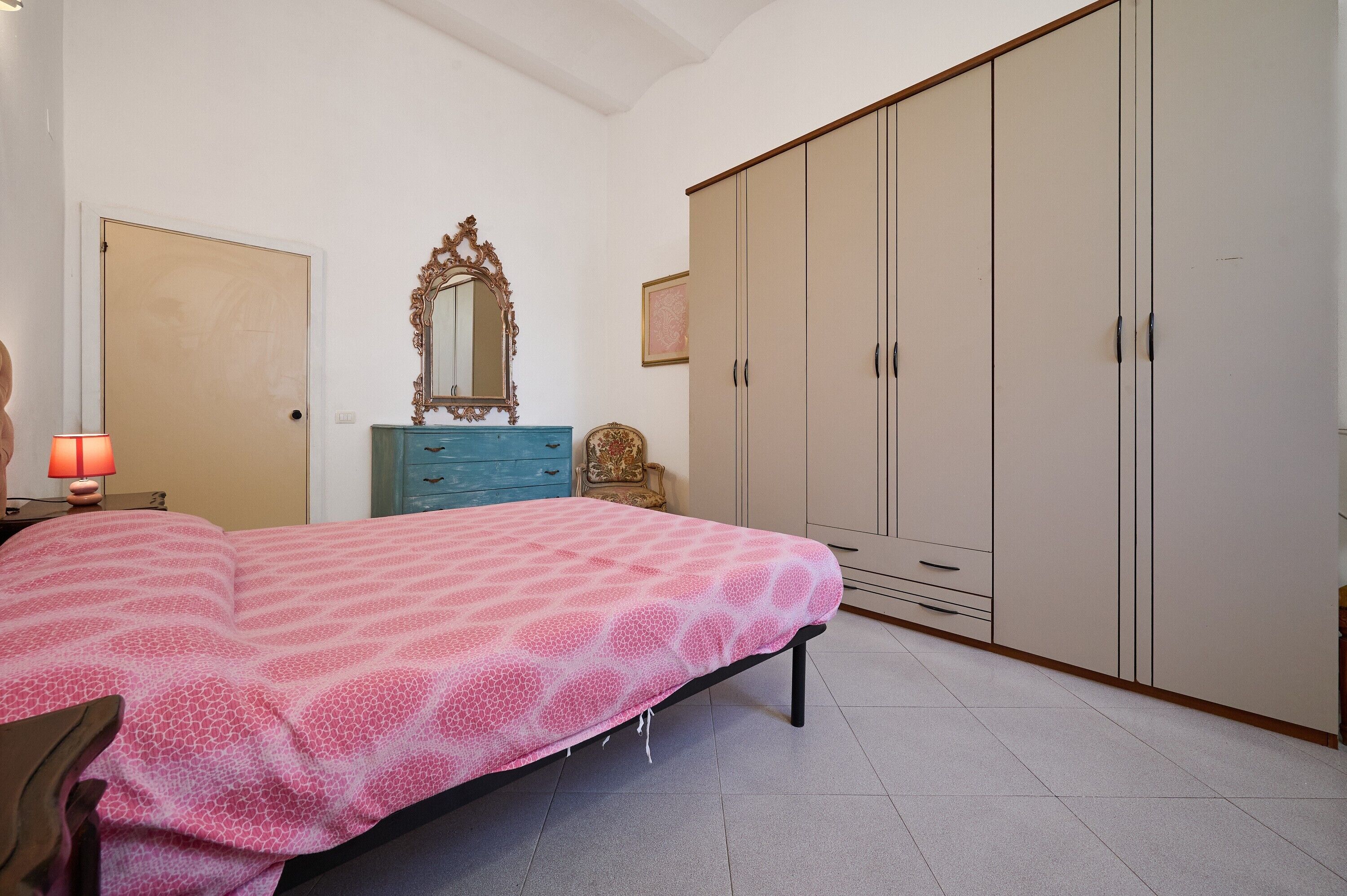 Un dormitorio con cama, cómoda, armario y espejo.