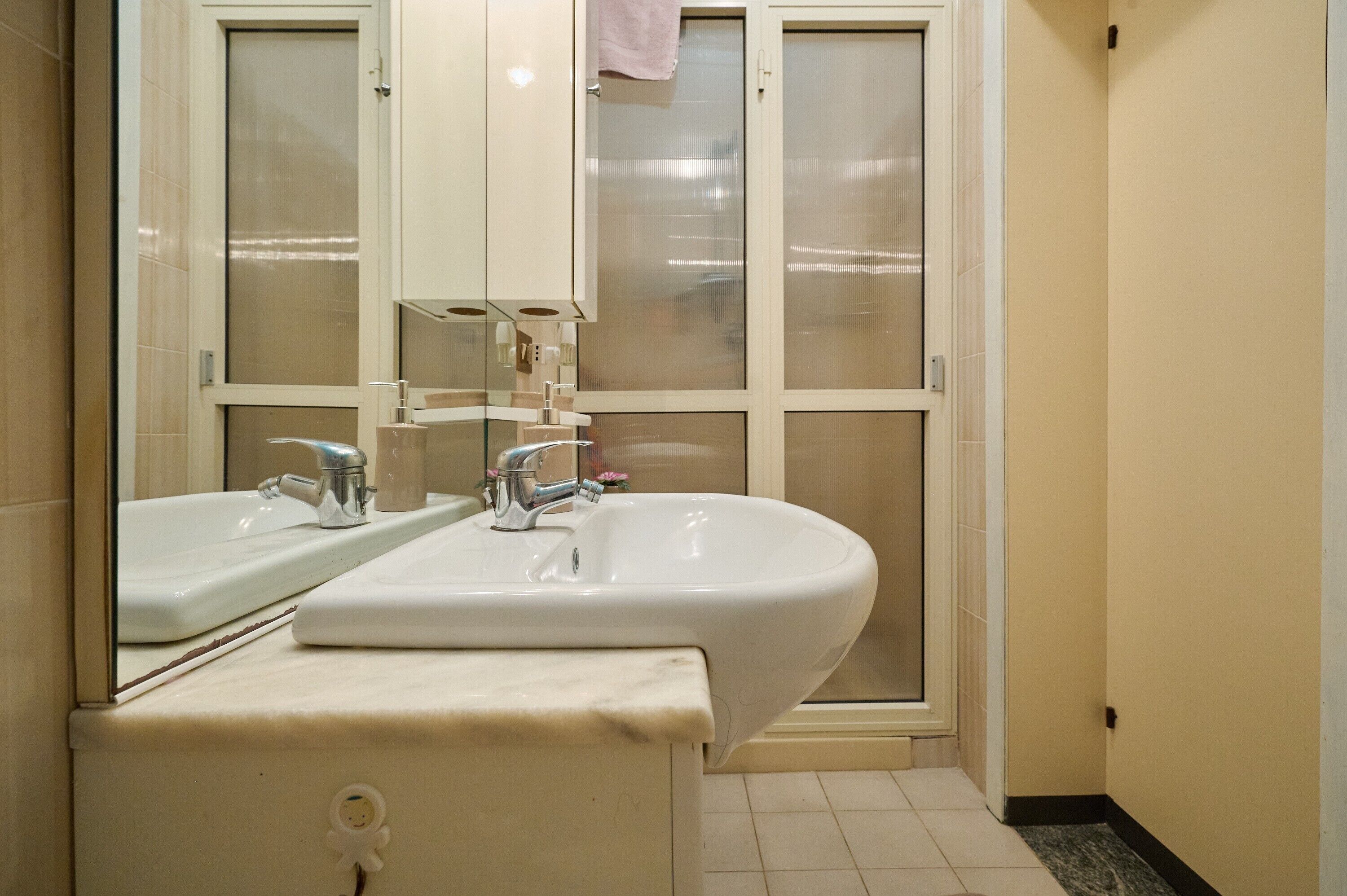 A bathroom with two sinks, a mirror, and a frosted glass shower door.