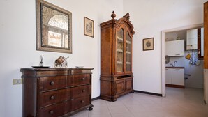 A room with a wooden dresser, a large mirror, and a cabinet with glass doors.