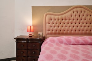 A bedroom with a tufted headboard, a bedside table with a lamp, and a patterned bedspread.