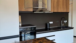 Una cocina moderna con una mesa de comedor de madera, sillas negras y una lámpara colgante original.