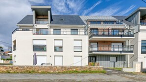 A modern multi-story residential building with balconies, large windows, and a stone retaining wall. - Apartment 'Port Lin Near the Ocean' with Balcony and Wi-Fi (Le Croisic)