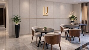 Eine moderne Hotelhalle mit minimalistischem Design, mit einer U-förmigen Rezeption, bequemen Sitzgelegenheiten und Topfpflanzen.