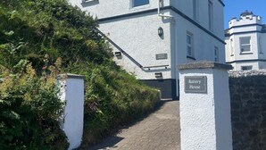 Un edificio bianco con una insegna che recita 'Battery House' all'ingresso.