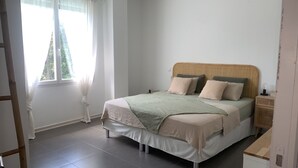 A bedroom with a bed, curtains, a bedside table, and a nightstand.