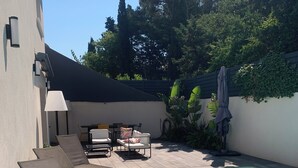 A poolside area with lounge chairs, a table, and a lamp.