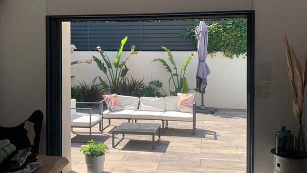 A modern living room with a sliding glass door leading to an outdoor patio area.