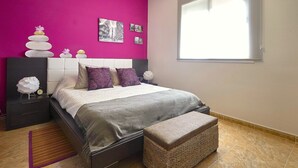 A bedroom with a bed, pillows, a bedside table, a nightstand, a window, and a wall with pictures. - Cozy house with pool (CT)
