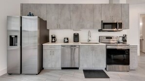 A modern kitchen with grey cabinets, stainless steel appliances, and a dishwasher. - Modern 2BR | Gym | Parking | Workspace (Dallas)