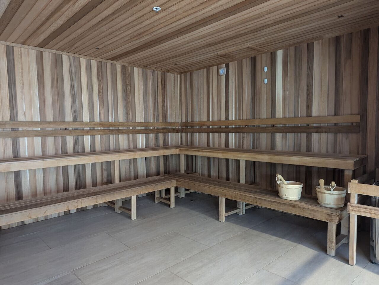 Un sauna avec des bancs en bois et un banc muni d’un seau et d’un mortier.