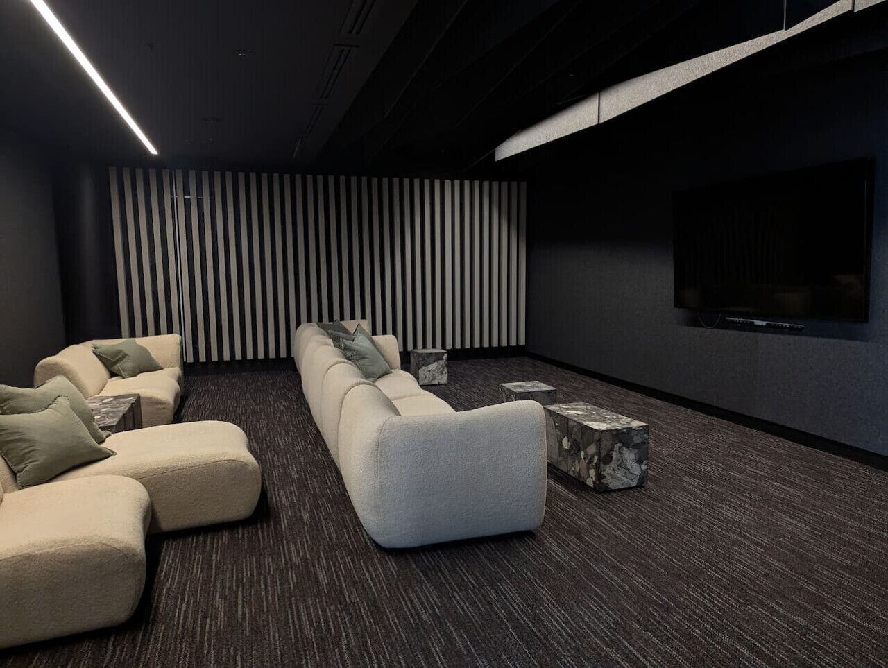 Een moderne thuisbioscoop met een hoekbank, een flatscreen-tv en een behang met patroon.