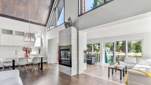 A spacious living area with a fireplace, a dining table with chairs, a sofa, and a coffee table. - Bora Nature | Private Spa & Lakefront (Shannon)