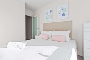 A hotel room with a large bed, white bedding, a beige headboard, and two abstract art pieces on the wall. - City View 2BR, FREE Parking, Bright & Central Apt (Melbourne)