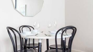 A dining area with a round table, four chairs, and a large mirror on the wall.