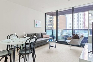 A modern living room with a dining area, large windows, and a view of the cityscape.
