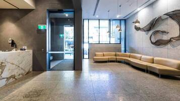 A modern lobby with a marble reception desk, a curved seating area, and a large abstract wall art piece.