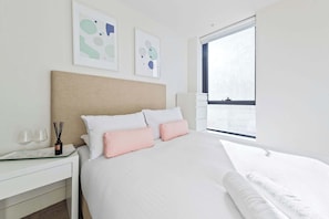 A neatly arranged hotel room with a bed, bedside table, and a window with a view.