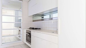 A modern kitchen with white cabinets, a stainless steel range hood, and a built-in oven. - City View 2BR, FREE Parking, Bright & Central Apt (Melbourne)