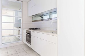 A modern kitchen with white cabinets, a stainless steel range hood, and a built-in oven. - City View 2BR, FREE Parking, Bright & Central Apt (Melbourne)