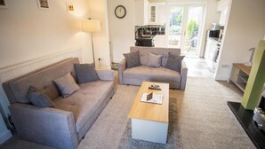 Un salon avec deux canapés gris, une table basse en bois et une lampe.