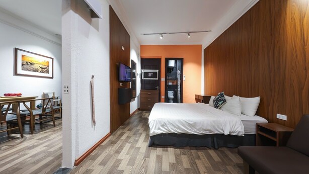 A compact hotel room with a bed, a small seating area, a kitchenette, and a dining table. - An Huy Apartment (Hanoi)