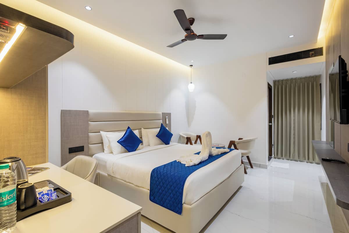 Une chambre d’hôtel moderne avec un grand lit, un bureau avec une bouteille d’eau et un ventilateur de plafond.