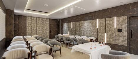 A conference room with rows of chairs, a table with water bottles, and a marble wall with a patterned design.
