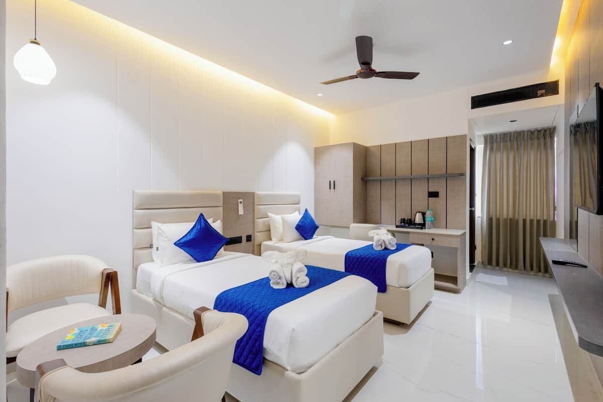 Une chambre d’hôtel moderne dotée de deux lits, d’un coin salon, d’une petite kitchenette et d’un ventilateur de plafond.