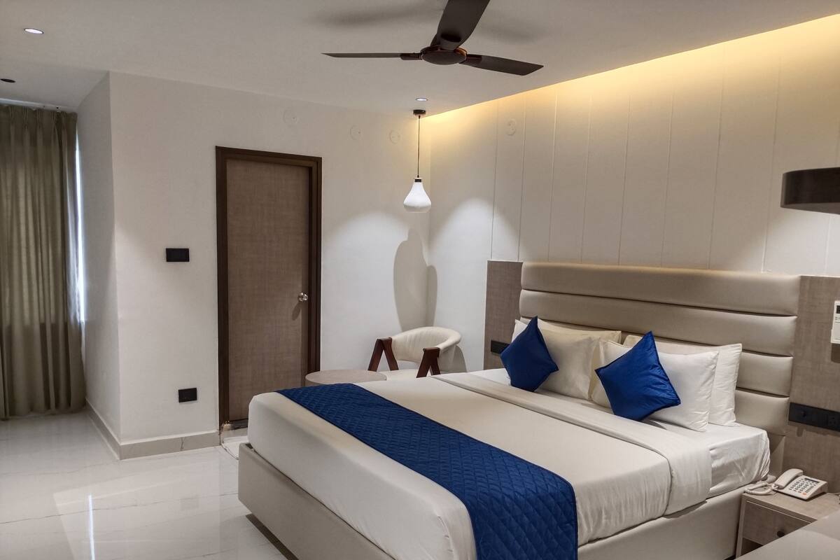 Une chambre d’hôtel moderne avec un grand lit, un ventilateur de plafond et une table de chevet avec un téléphone.