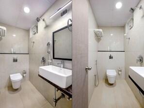 A modern bathroom with a white sink, a mirror, a shower, and a toilet. - ECKO La Maniere Business Hotels (Hyderabad)