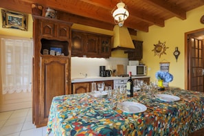 Un coin repas avec une table dressée pour quatre personnes, des meubles en bois, un four à micro-ondes et un luminaire décoratif au plafond.
