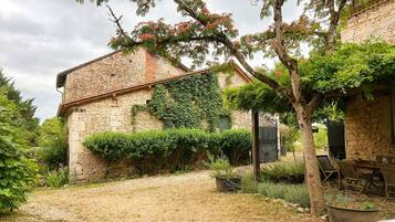 A stone building with ivy-covered walls and a gravel courtyard.