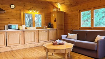 A cozy cabin interior with wooden walls, a kitchenette, a sofa, and a dining table.