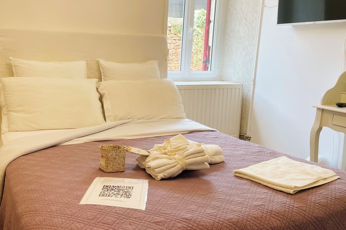 Un lit bien fait, avec des draps blancs, une serviette pliée et un code QR sur la couverture.