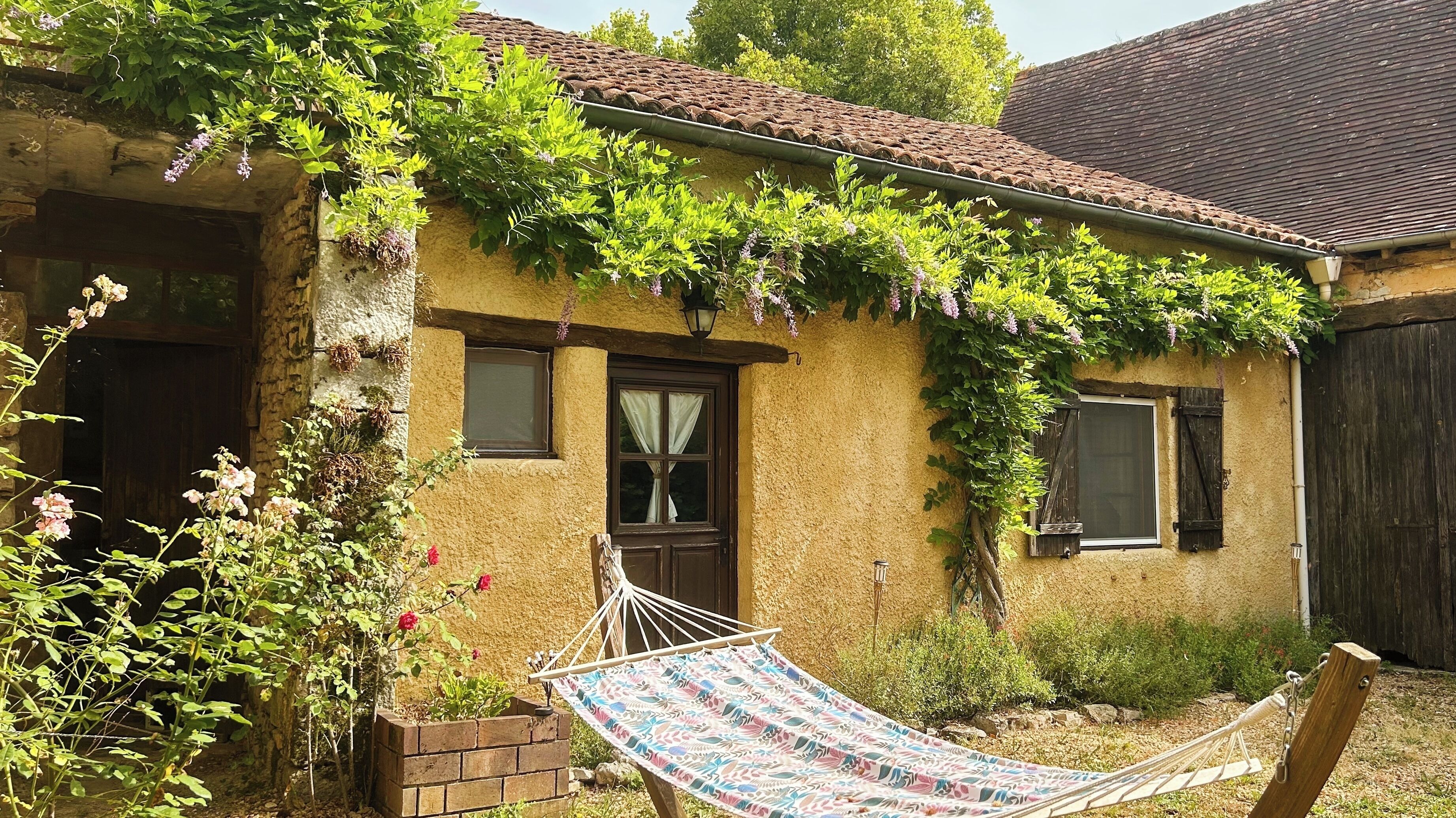 Una casa rústica con fachada de ladrillo, puerta de madera y ventana con contraventanas.