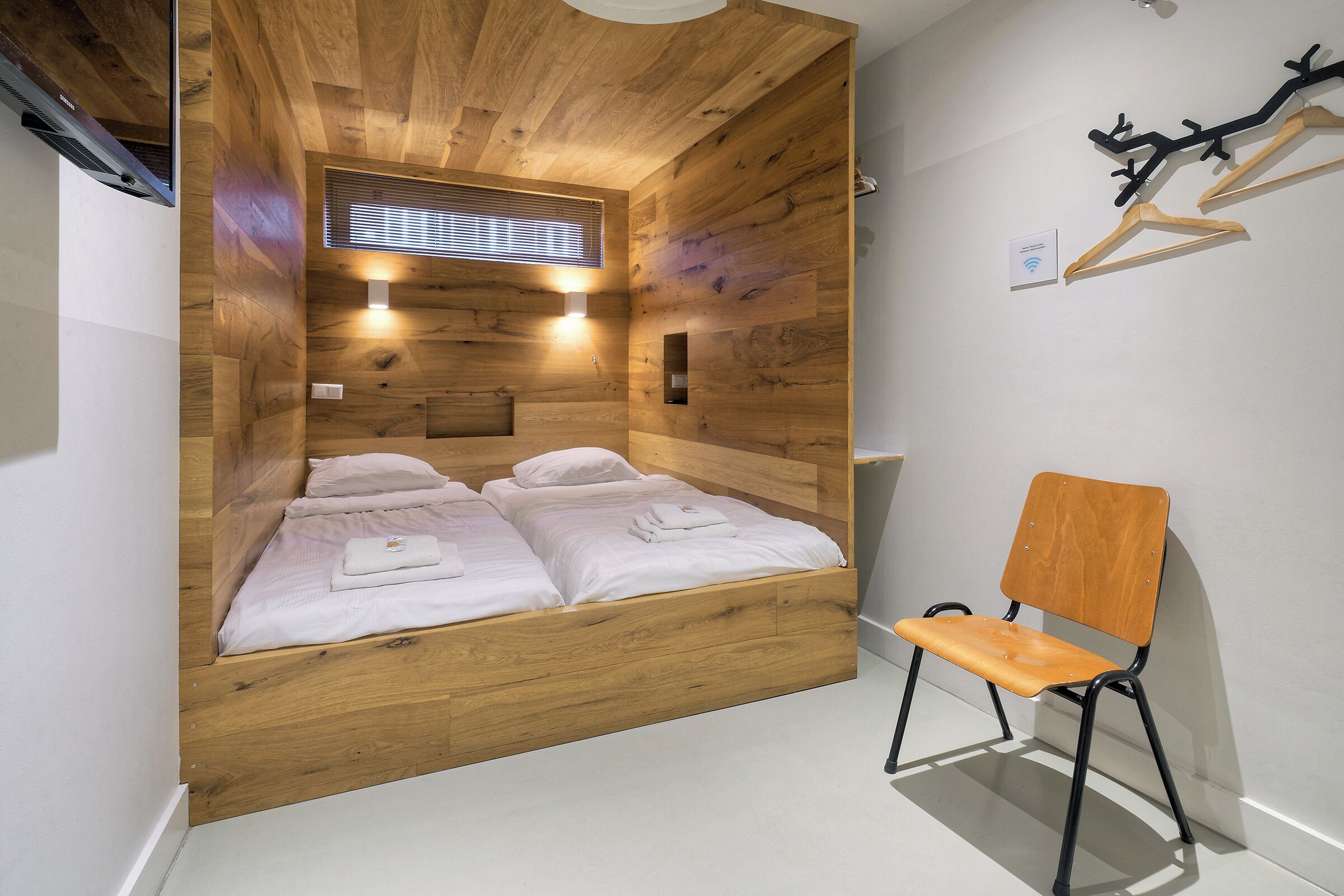 A room with a wooden bed, a wooden chair, and a wooden ceiling.