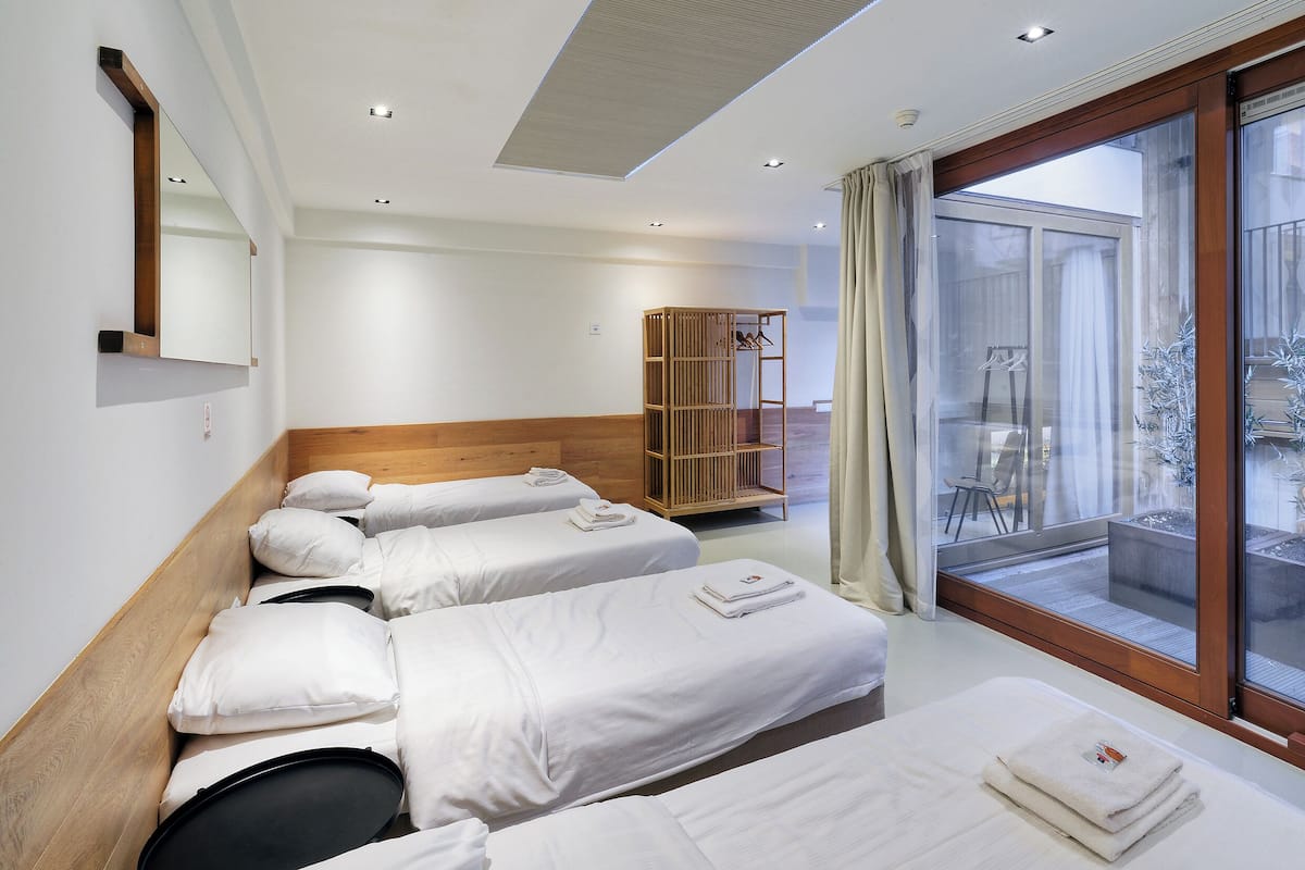 Een hotelkamer met twee bedden, een houten garderobe, een grote schuifglazen deur naar het balkon, en een spiegel aan de muur.