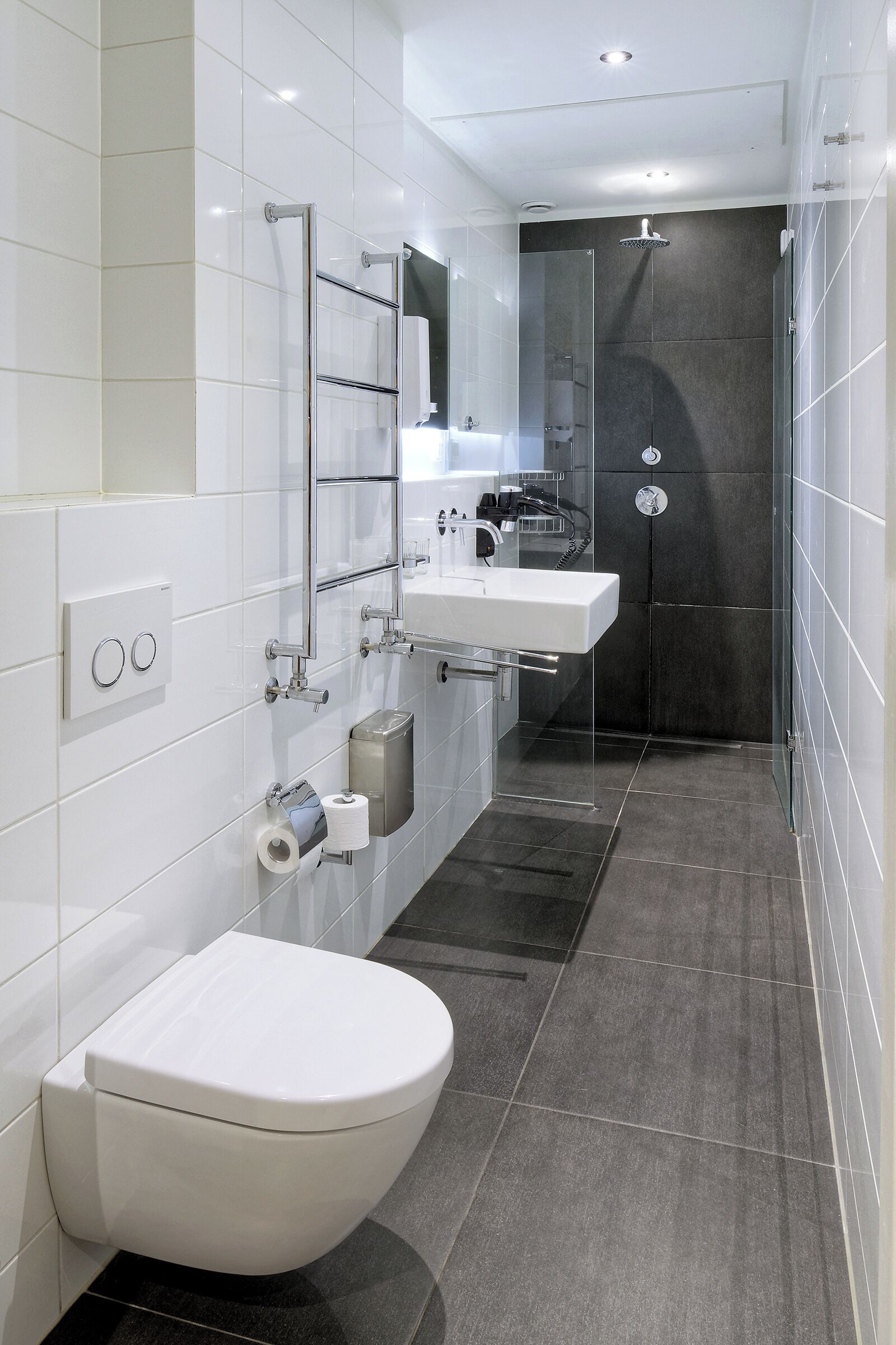 Ein modernes Badezimmer mit Toilette, Waschbecken, Spiegel und Duschbereich.