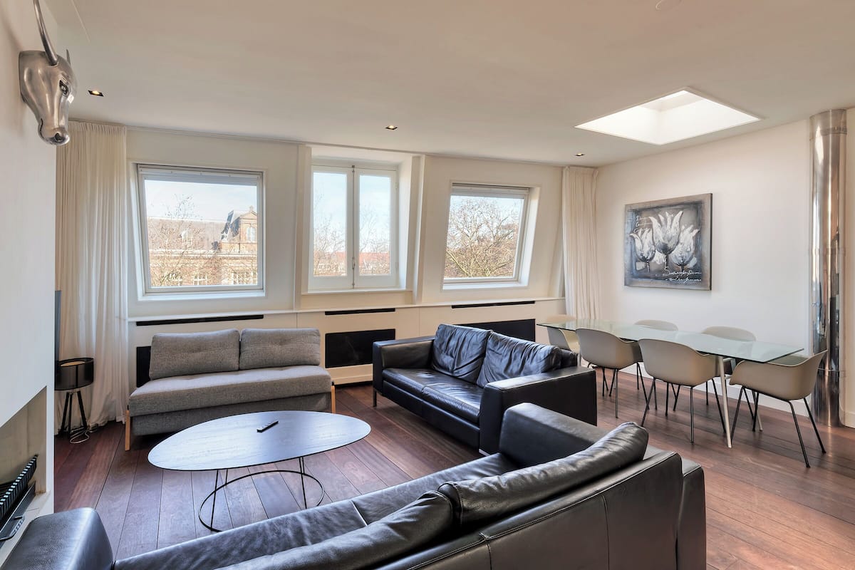 Een moderne woonkamer met een bank, een salontafel en een eethoek met stoelen en een tafel.