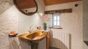 A rustic bathroom with a wooden sink, a round mirror, a small window, and a radiator. - Holiday Home 'Ty Coz' with Private Terrace, Private Garden and Wi-Fi (Lanvellec)