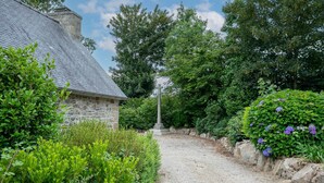 A stone building with a gravel path leading to a central monument. - Holiday Home 'Ty Coz' with Private Terrace, Private Garden and Wi-Fi (Lanvellec)