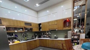 A modern kitchen with wooden cabinets, a dining area with a table and chairs, and a tiled floor. - Imperia Sky Garden Dream Loft (Hanoi)