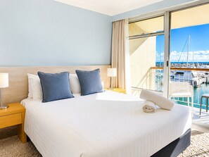 A hotel room with a large bed, a nightstand, a lamp, and a view of a marina. - Amazing location on Fisherman’s Wharf only minutes to vibrant Fremantle nightlife and cafes. Enjoy the infamous West Australian Sunsets on your private balcony. (Fremantle)