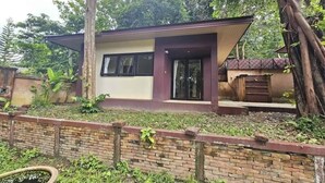 Une maison moderne de plain-pied, dotée d’un toit plat, de grandes fenêtres et d’un mur de briques en premier plan.