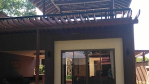 Un bâtiment doté d’une entrée abritée, d’un patio aménagé avec des sièges et offrant une vue sur l’intérieur.