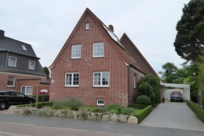 Une maison en briques rouges, avec un toit en pente, une allée et une voiture garée dans l’allée.