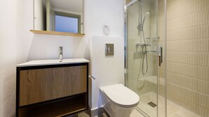 A modern bathroom with a wooden vanity, a white toilet, and a glass-enclosed shower area. - Phaedrus Living: Paros Cycladic Residences 2 (Piso Livadi)