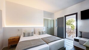 A modern bedroom with two beds, a wooden nightstand, a sofa, and a TV. - Phaedrus Living: Paros Cycladic Residences 2 (Piso Livadi)