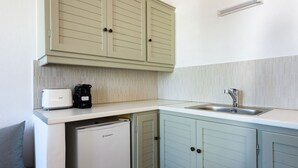 A compact kitchen with a built-in refrigerator, a coffee maker, and a sink. - Phaedrus Living: Paros Cycladic Residences 2 (Piso Livadi)