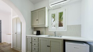 A compact kitchen with a built-in dishwasher, a window with a view of palm trees, and a white countertop.